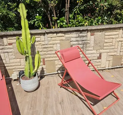 a red chair and a cactus on a patio at Poolside Apartment Barcelona Sant Cugat in Sant Cugat del Vallès