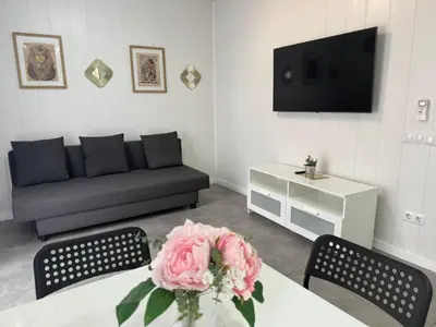 a living room with a couch and a table with a flower at Sunny Terrace Apartment in Santa Coloma de Gramanet