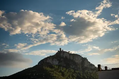 a mountain with a building on top of it at Masia Cal Noia - Rural Villas in Castellví de la Marca