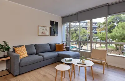 a living room with a couch and tables and windows at Casa Cosi - Camp Nou in Barcelona