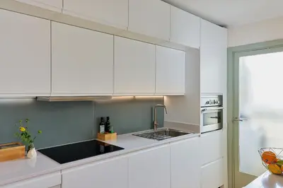 a white kitchen with a sink and white cabinets at Casa Cosi - Camp Nou in Barcelona
