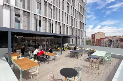 a balcony with tables and chairs on a building at Urbany Hostel Barcelona in Barcelona