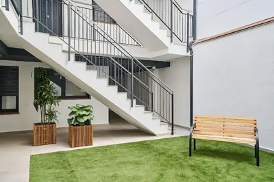 a wooden bench in front of a building with a staircase at Tr3sor 11 in Calella