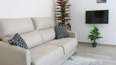 a couch in a living room with two pillows on it at El Barco Aparta Hotel in Hospitalet de Llobregat