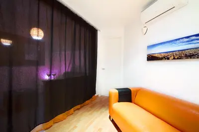 an orange couch in a room with a black curtain at Apartment Gaudi XL in Barcelona