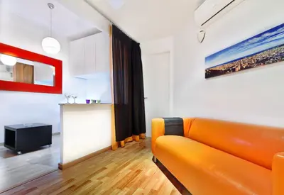 a living room with an orange couch and paintings at Apartment Gaudi XL in Barcelona
