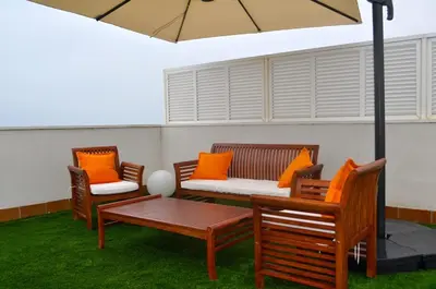 a patio with chairs and a table and an umbrella at Ático con vistas al mar, solarium privado y piscina in Sitges