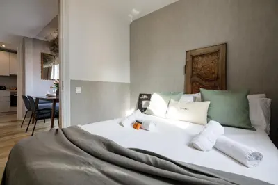 a bedroom with a bed with white sheets and green pillows at En Ville Boutique Apartments Calabria in Barcelona
