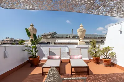 a balcony with chairs and plants on a roof at En Ville Boutique Apartments Calabria in Barcelona
