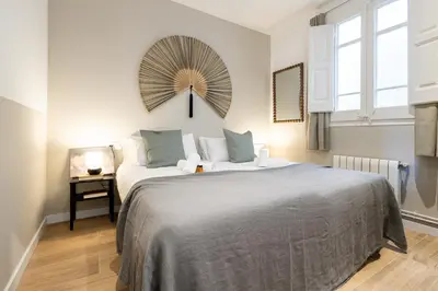 a bedroom with a large bed and a mirror on the wall at En Ville Boutique Apartments Calabria in Barcelona