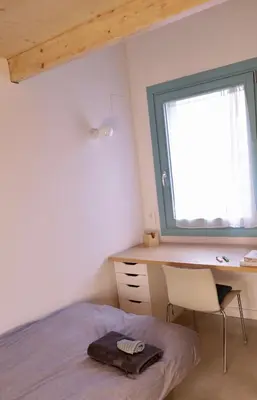 a bedroom with a bed and a desk and a window at Independent duplex in a stately villa in Sant Cugat del Vallès