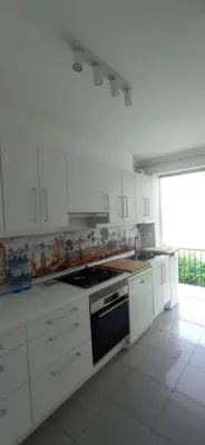 a kitchen with white cabinets and a stove top oven at Quiet cozy apartment near beach in Sitges