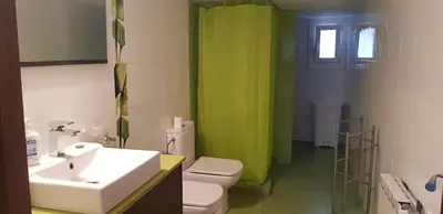 a bathroom with a sink toilet and a green shower curtain at Tranquilidad y Privacidad in Cánoves