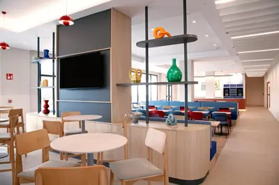 a waiting room with tables and chairs and a tv at Holiday Inn Express & Suites Barcelona - Sabadell by IHG in Sabadell