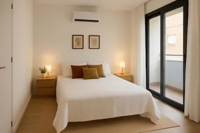 a white bedroom with a white bed and two lamps at D&G casas in El Prat de Llobregat