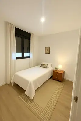 a white bedroom with a bed and a window at D&G casas in El Prat de Llobregat