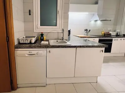 a white kitchen with a sink and a counter at Acojedor apartamento, centro con patio in Sabadell