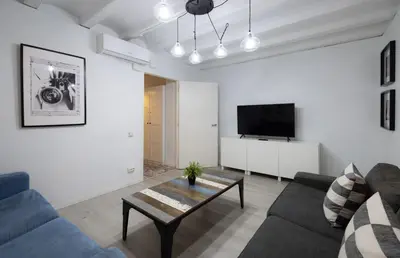 a living room with a couch and a tv at Stay U-nique Roger Llúria in Barcelona