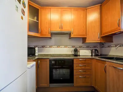 a kitchen with wooden cabinets and a black dishwasher at Horizon Views by Hello Homes Sitges in Sitges