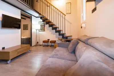 a living room with a large couch and stairs at Cozy Equipped Duplex in Poblenou Ideal for 4 Guests and Close to Public Transport in Barcelona