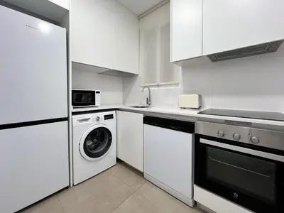 a kitchen with white cabinets and a washer and dryer at Stay U-nique Apartments Balmes III in Barcelona