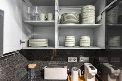a kitchen with white plates and dishes on shelves at Beachside apartment in Barcelona