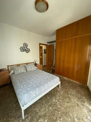 a bedroom with a bed and a wooden cabinet at Casa la Luna in Badalona