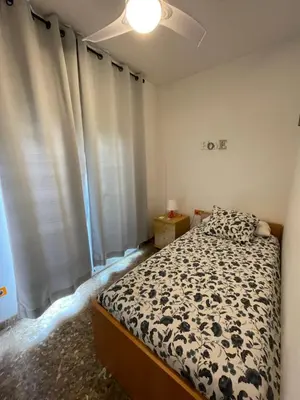 a bedroom with a bed and a window with curtains at Casa la Luna in Badalona