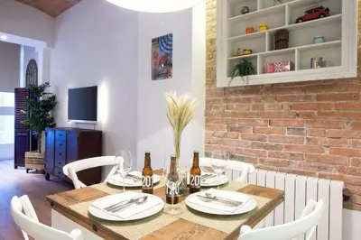 a dining room with a wooden table and white chairs at Bright Industrial Loft Barcelona Center in Barcelona