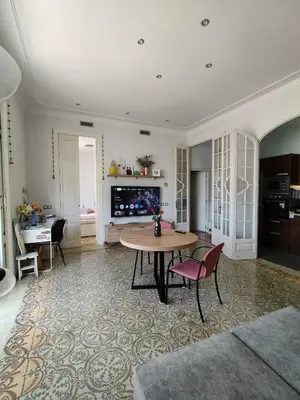 a living room with a table and chairs and a tv at Pis històric modernista al centre de Manresa in Manresa
