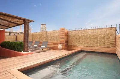 a backyard with a swimming pool and a wooden deck at Enjoybcn Colon Apartments in Barcelona