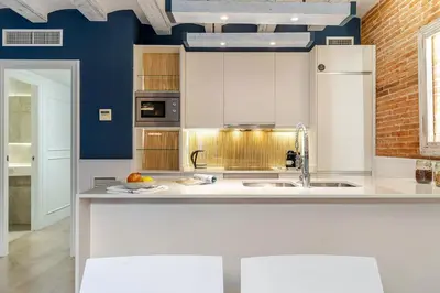 a kitchen with white cabinets and blue walls at Enjoybcn Colon Apartments in Barcelona