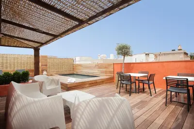 a patio with white chairs and a table on a deck at Enjoybcn Colon Apartments in Barcelona