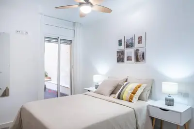 a white bedroom with a bed and a ceiling fan at Homenfun Barcelona Los Bunkers in Barcelona