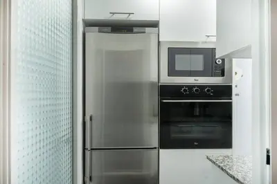 a kitchen with a stainless steel refrigerator and a microwave at Homenfun Barcelona Los Bunkers in Barcelona