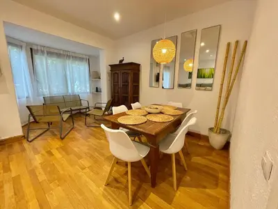 a dining room with a wooden table and white chairs at Practical, 3 double bedrooms, 7' Sagrada Familia in Barcelona