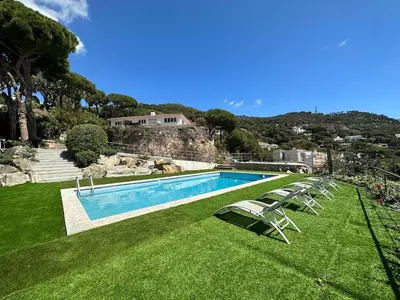 a swimming pool with lawn chairs and a house at Casanova, villa with Barcelona's skyline in Cabrils