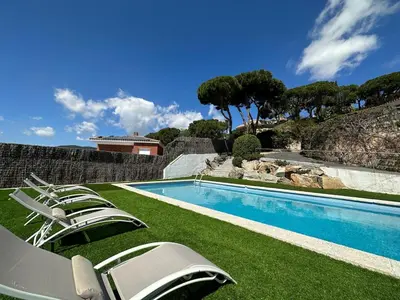 a swimming pool with lounge chairs on the grass at Casanova, villa with Barcelona's skyline in Cabrils