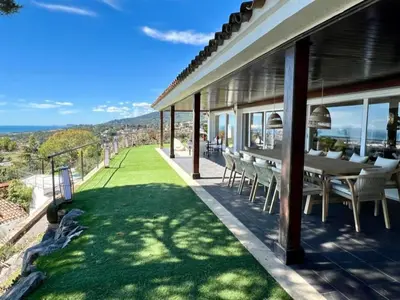 a house with a patio with a table and chairs at Casanova, villa with Barcelona's skyline in Cabrils