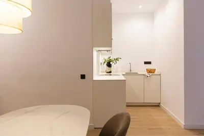 a white kitchen with a white counter and a table at Barcelona - Gracia P-A in Barcelona