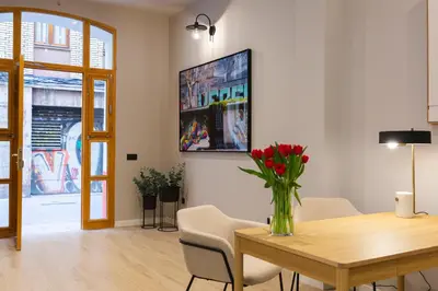 a dining room with a table and a vase with red flowers at Barcelona - Gracia 3-B in Barcelona