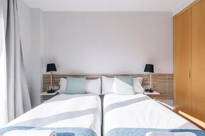 two beds in a bedroom with two lamps and curtains at Weflating Barcelona Sants in Barcelona