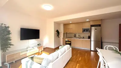 a living room with a white couch and a kitchen at Luminoso apartamento by Prestigi in Terrassa