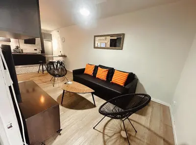 a living room with a black couch and orange pillows at 2 bedrooms apartment in Barcelona F1 in Hospitalet de Llobregat