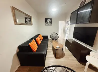 a living room with a black leather couch and a flat screen tv at 2 bedrooms apartment in Barcelona F1 in Hospitalet de Llobregat