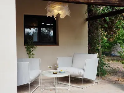 two white chairs and a table in front of a building at Accommodation in a 13th century Catalan farmhouse in Terrassa