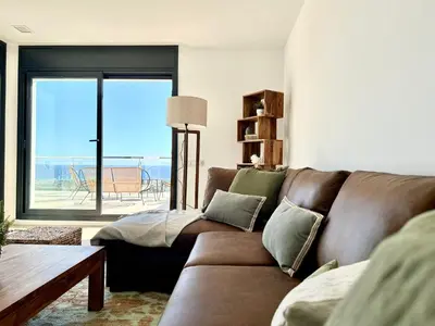 a living room with a brown couch and a table at Les Flors de Cunit Villa Cedra in Cunit