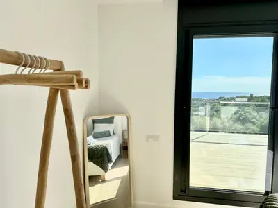 a bedroom with a mirror next to a window at Les Flors de Cunit Villa Cedra in Cunit