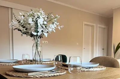 a table with plates and a vase of white flowers at Sunny & remodeled Apartment in Sant Boi del Llobregat