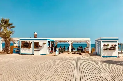a boardwalk on the beach with a gazebo and the ocean at Great apartment with a pool on the beach in Barcelona in Badalona